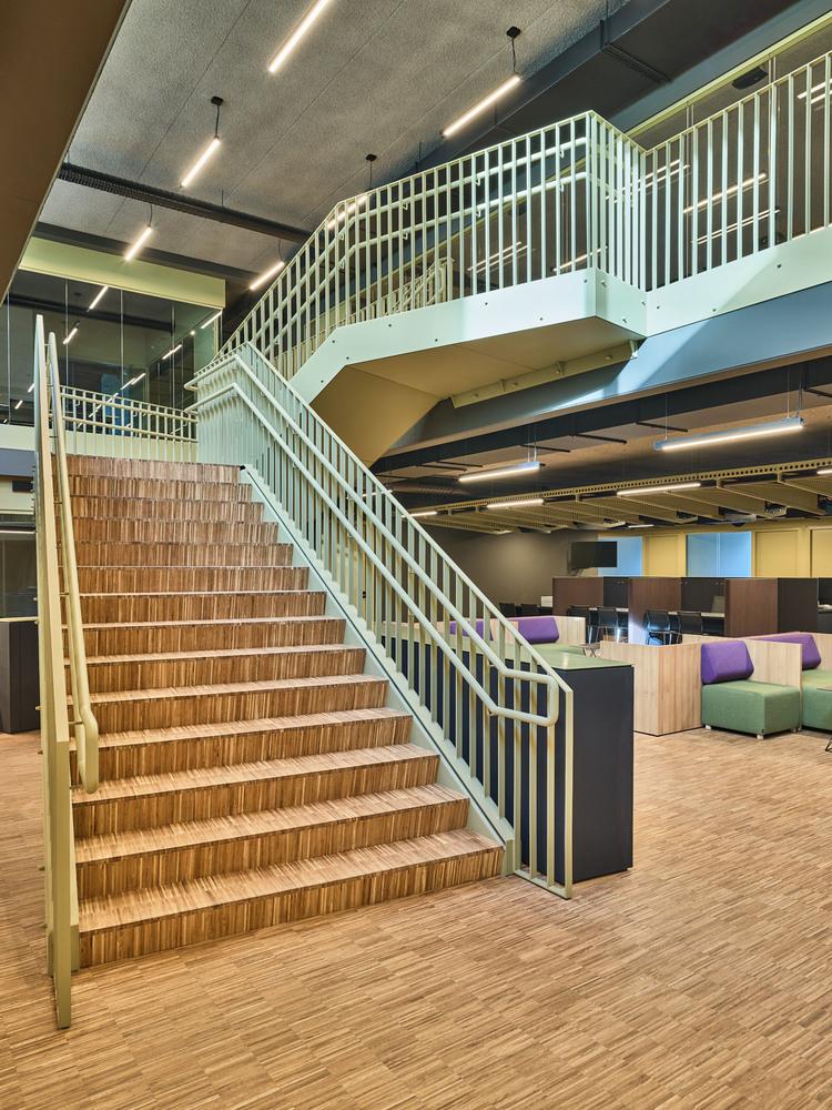 Wooden staircase in a modern office interior with acoustic ceiling panels for better sound absorption