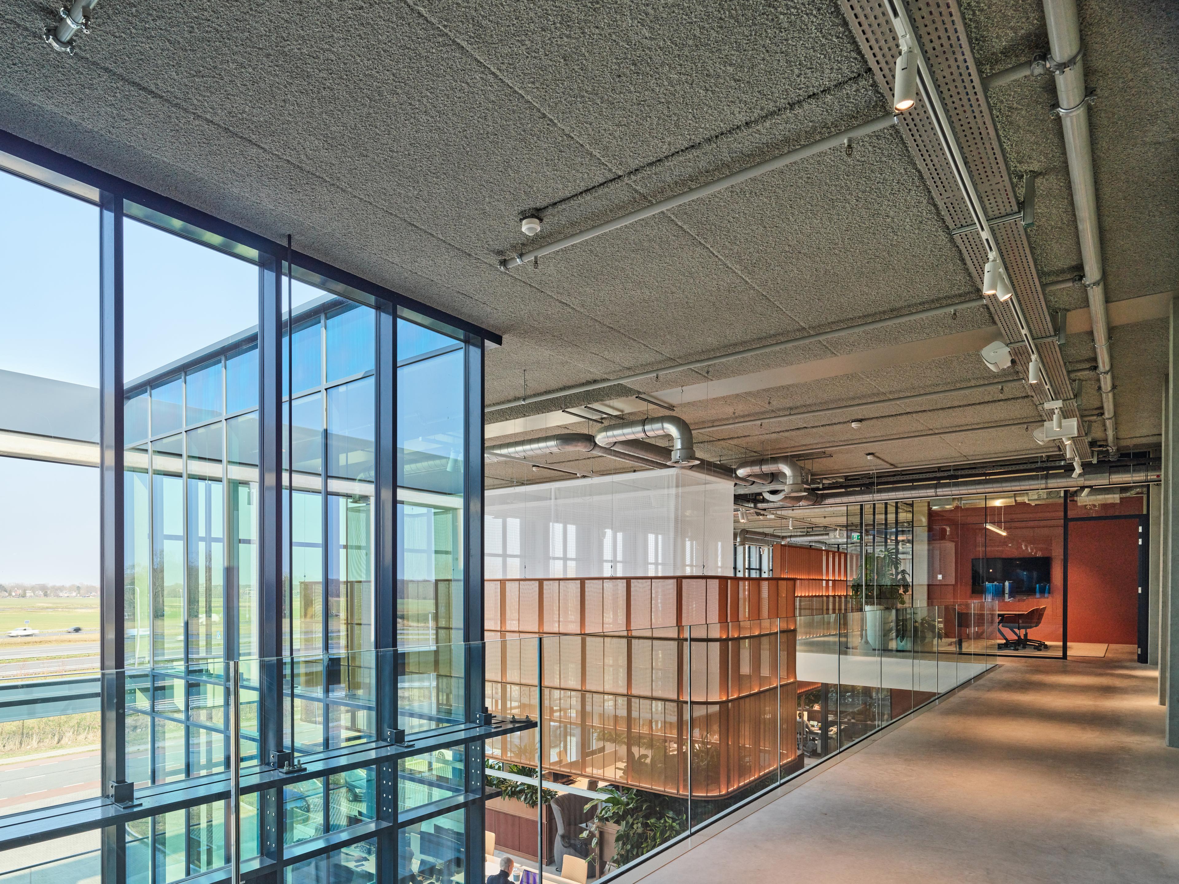 Kantoor Vercom met Acospray® DC3 in ILA grey, aangebracht door Acosorb op het volledige plafond. Het akoestisch spuitwerk integreert zichtbare installaties in een rustig, uniform plafondsysteem.